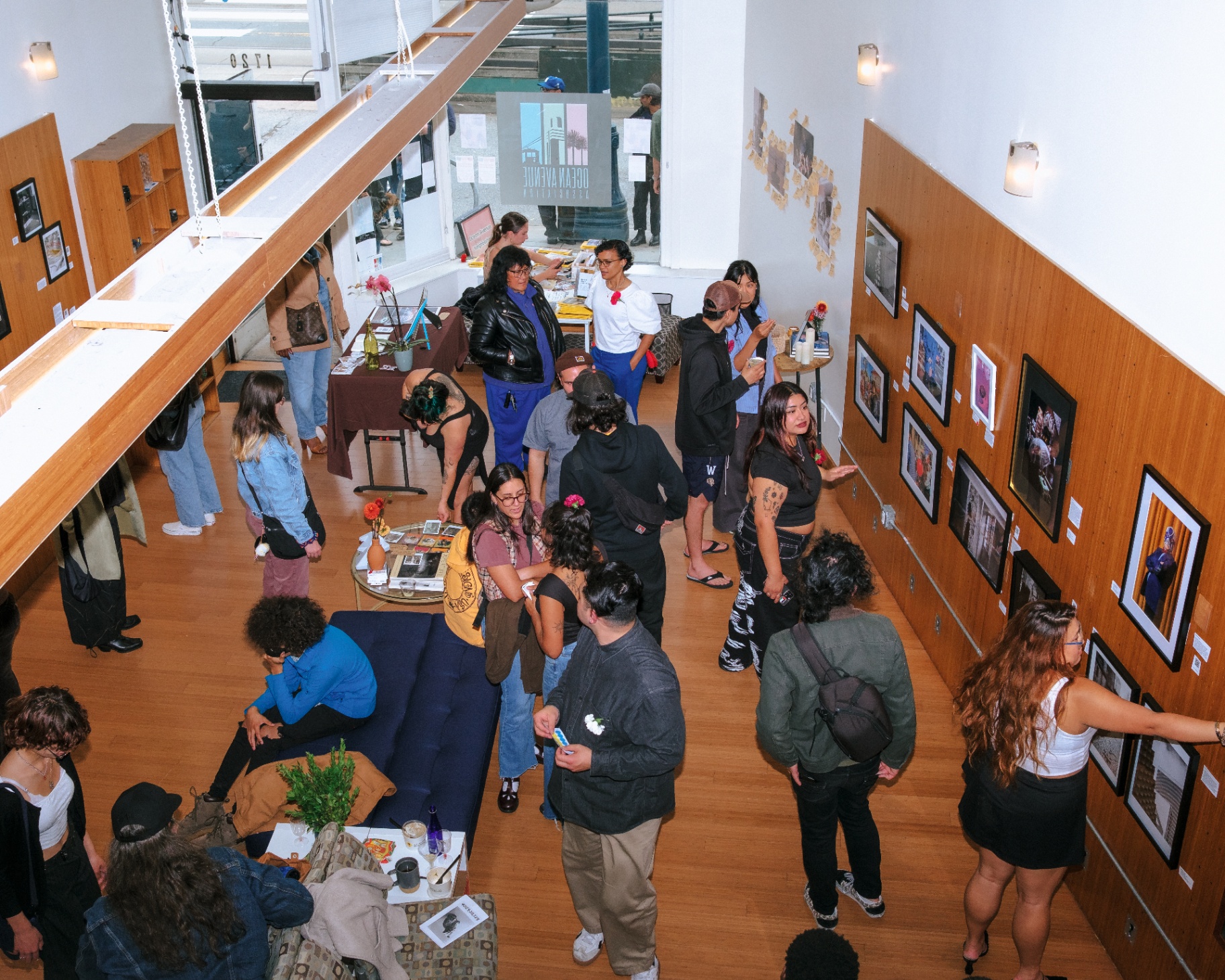 Overhead view of visitors at a gallery opening looking at framed photographs on a wood-paneled wall